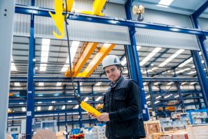 Worker using remote control crane in modern manufacturing facility
